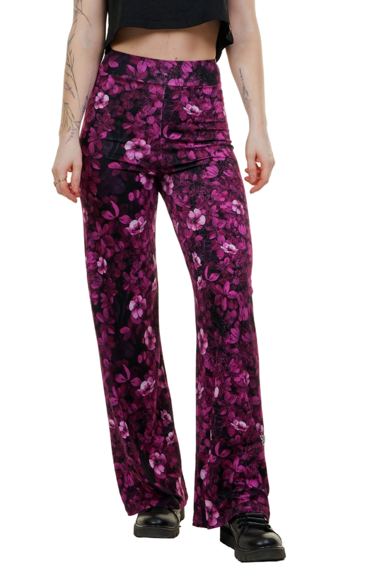 Frau trägt die weit geschnittene Marlene-Hose "Pink Flower" mit pinkfarbenem Blumenmuster zu einem schwarzen Crop-Top und Boots.