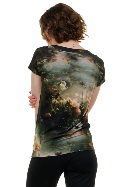 Hochwertiges Damen-T-Shirt 'Teichrose' (Pixie-Schnitt), Made in Berlin. Das Bild zeigt das florale Shirt im Nature-Core-Stil kombiniert mit schwarzen Leggings in einer entspannten Gartenatmosphäre.